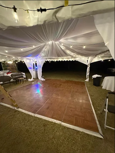 Dance floor under an Apex frame tent with bistro lighting overhead